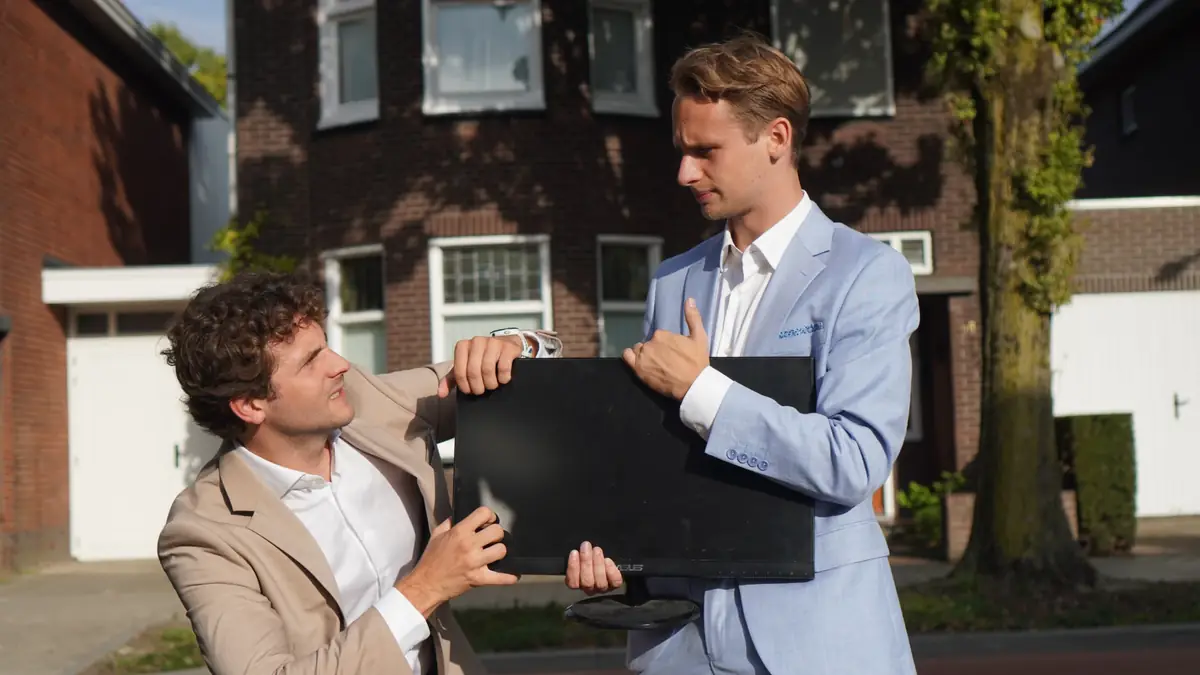 Twee mensen dragen samen een oude monitor